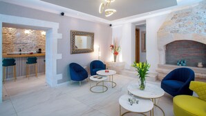 A modern living room with a stone wall, a fireplace, and a bar area. - Hotel Casa Moazzo (Rethymno)
