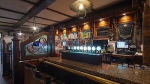 A bar area with a granite countertop, bar stools, a beer tap display, and a vintage television. - Dooly's Hotel  (Birr)