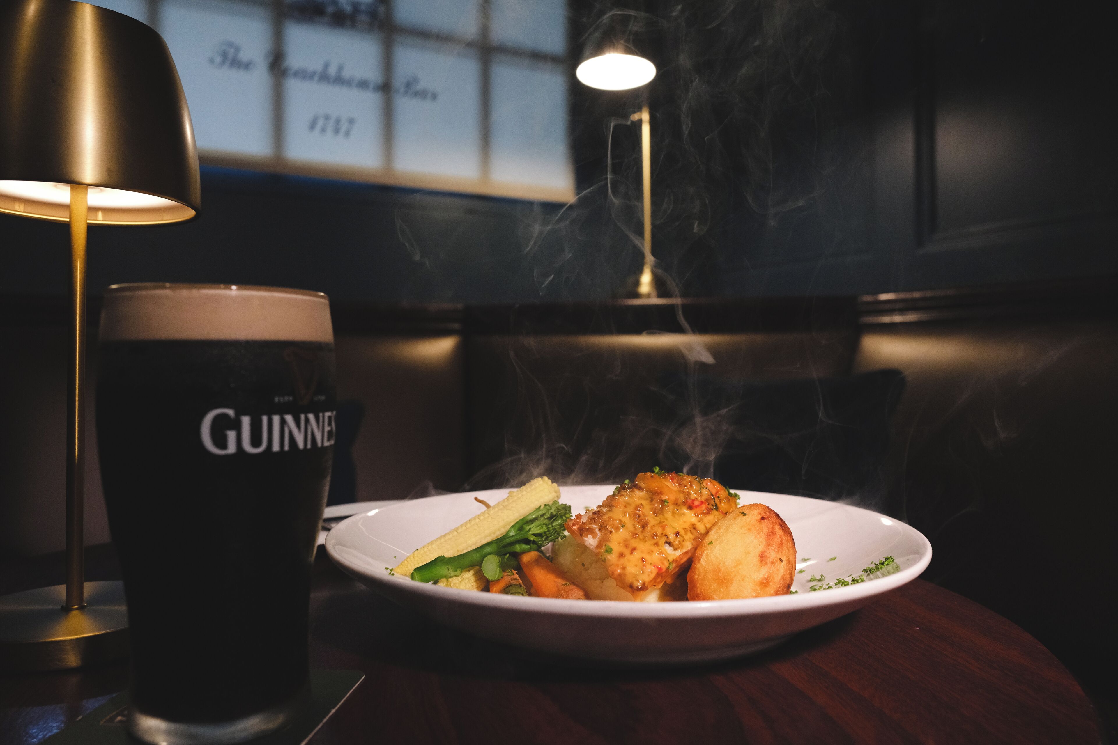 Een bord eten met een glas Guinness bier op een tafel.