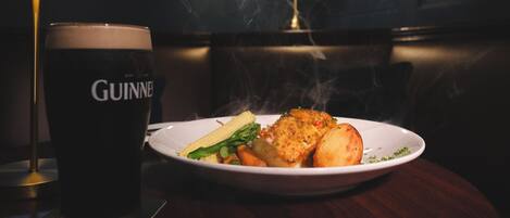 Een bord eten met een glas Guinness bier op een tafel.