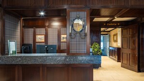A reception area with a marble counter, wooden paneling, framed artwork, and a sign for the toilet. - Dooly's Hotel  (Birr)