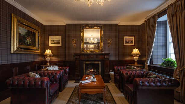 A formal sitting room with leather sofas, a fireplace, and framed artwork on the walls. - Dooly's Hotel  (Birr)