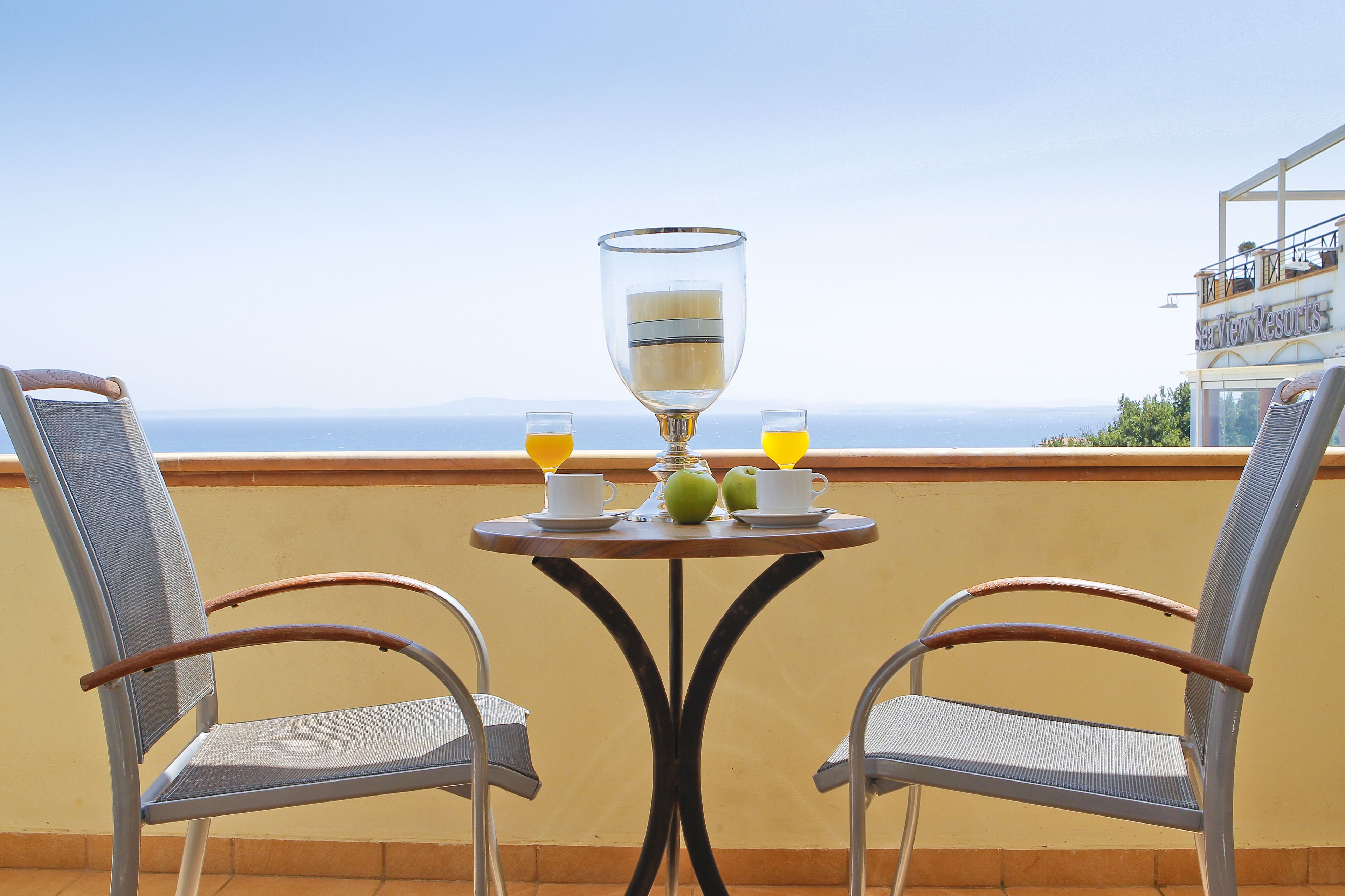 Ett bord med två stolar, ett glas och två glas apelsinjuice, med utsikt över ett vackert landskap.
