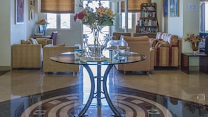 Un vestíbulo espacioso con una mesa redonda central, una araña y un suelo con diseño.