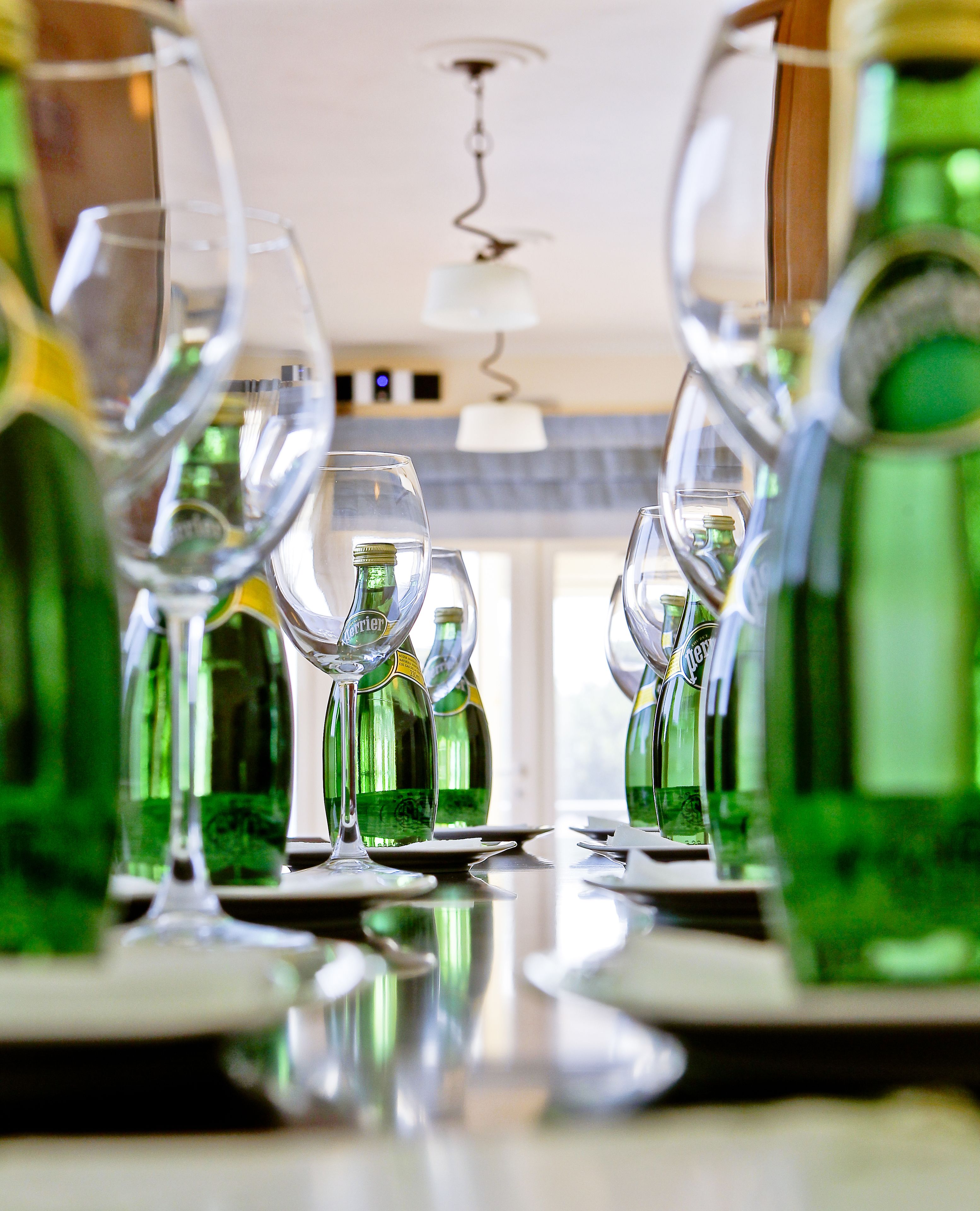 Una mesa de comedor con varias copas y botellas de vino, indicando un ambiente propicio para una comida o reunión.