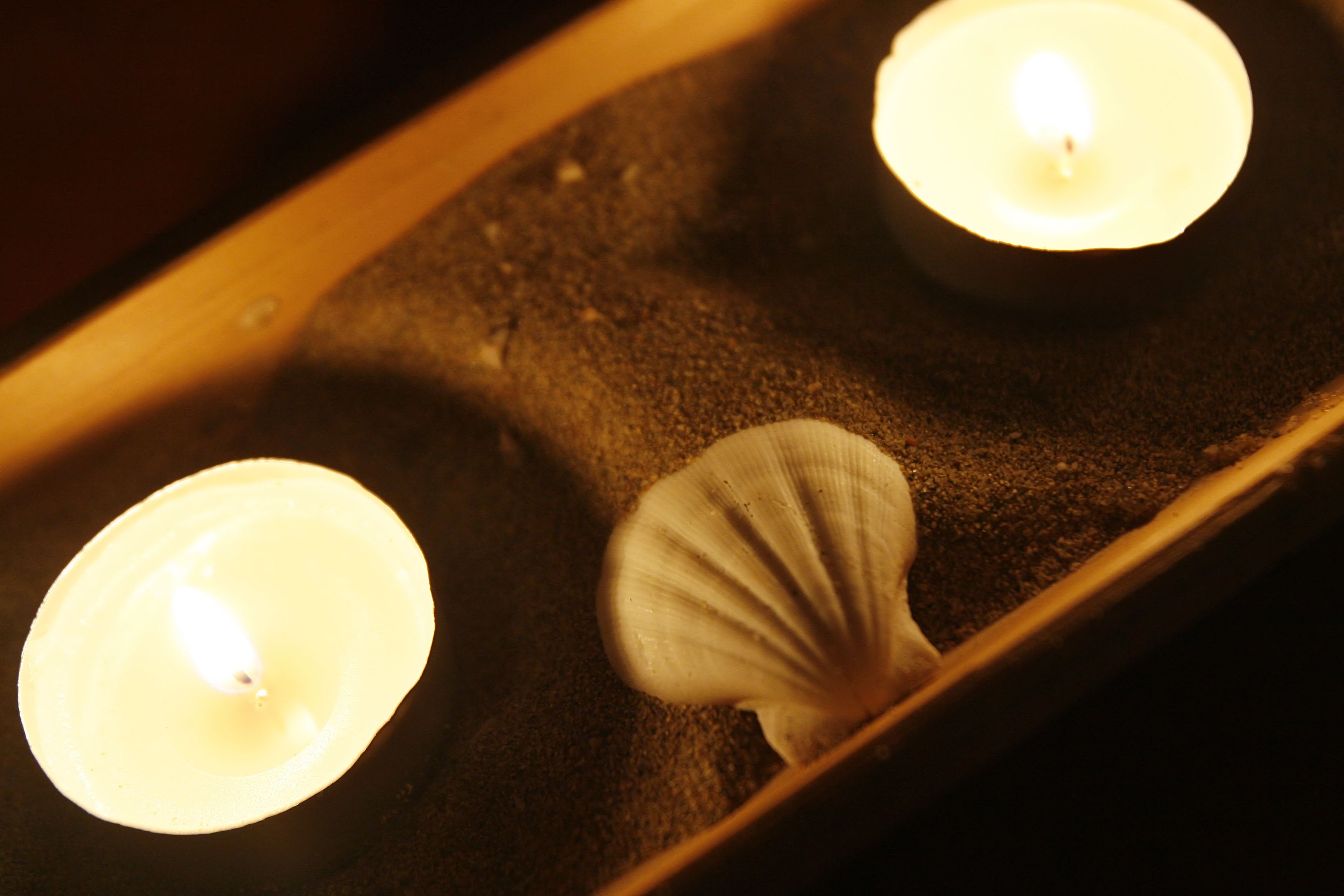 A candlelit scene with a shell on a textured surface.