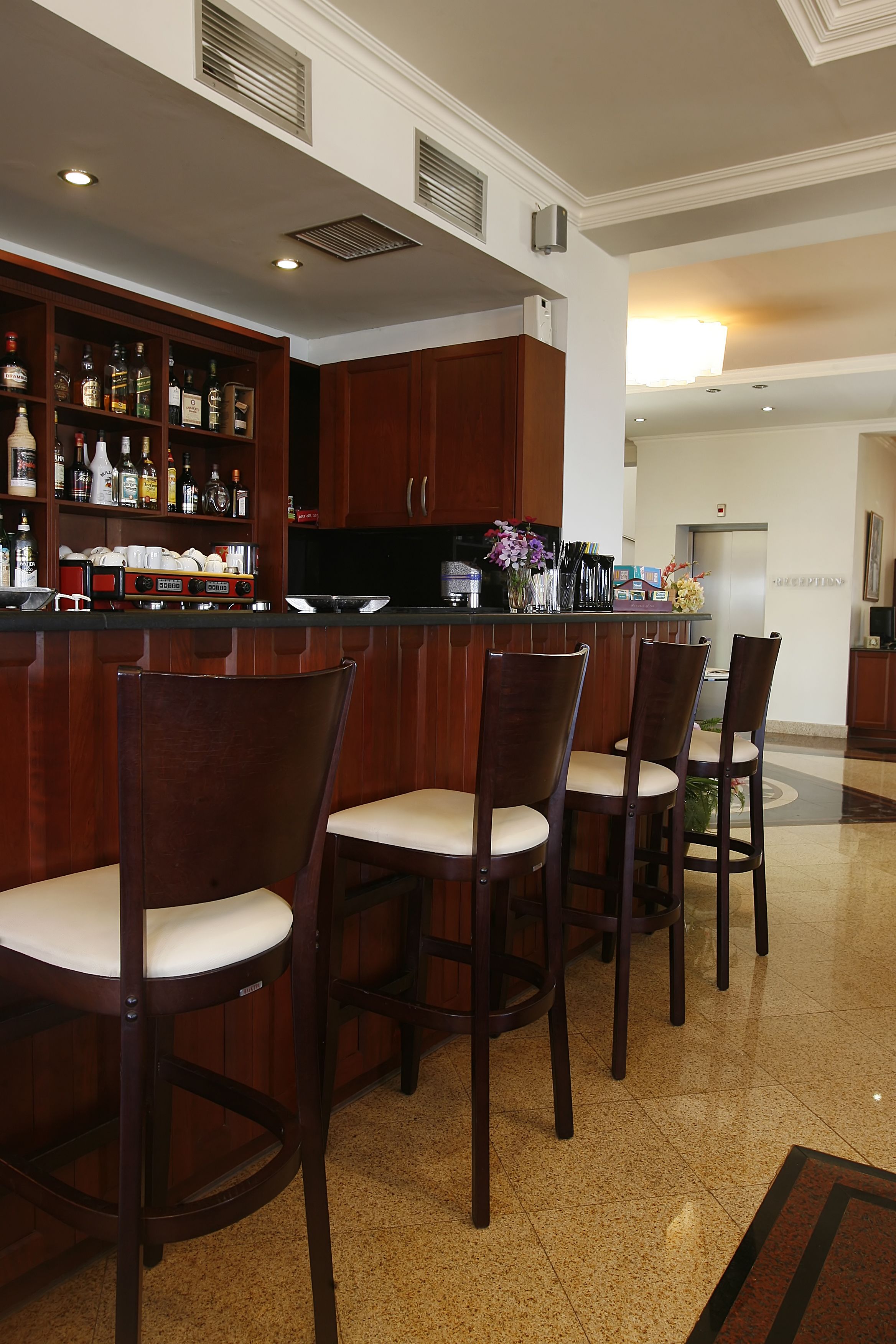 Een bar met houten stoelen en een bar waarop flessen staan.