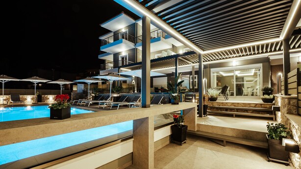 Ein moderner Poolbereich im Freien mit terrassenförmigen Sitzgelegenheiten und Kübelpflanzen.