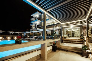 Una piscina al aire libre, sombrillas, sillones reclinables de piscina