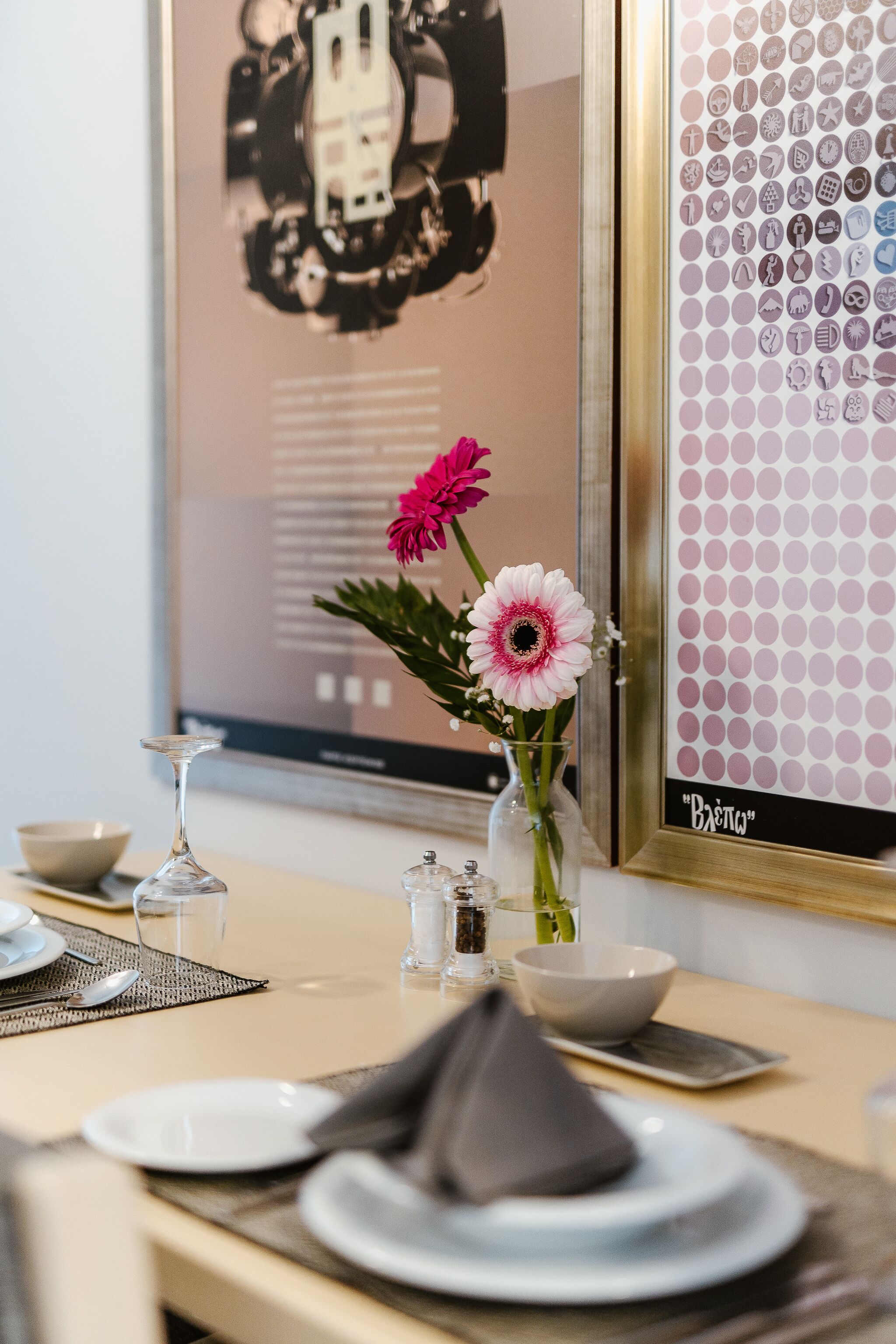 A dining table set with plates, a vase with flowers, and a framed picture.