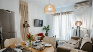 Ein modernes Wohnzimmer mit Essbereich, einer Couch, einem Fernseher und einer Pflanze.
