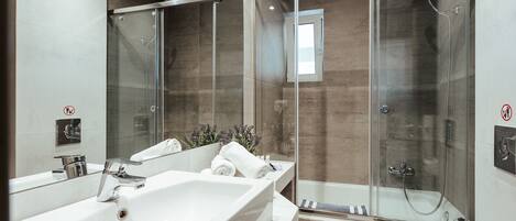 A modern bathroom with a large white bathtub, a glass-enclosed shower, and a separate toilet area.