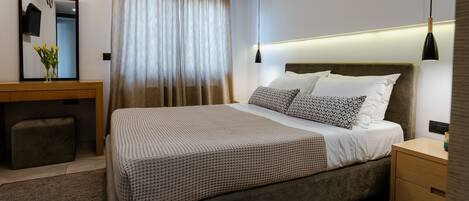 Quarto de hotel moderno com uma cama grande, mesas de cabeceira, escrivaninha e um espelho.