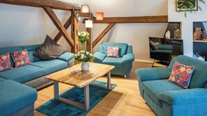 Una sala de estar acogedora con sofás azules, una mesa de centro de madera y un televisor.