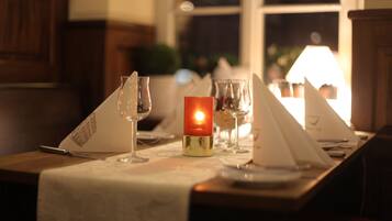 A table set for dining with a lit candle, wine glasses, and a menu.