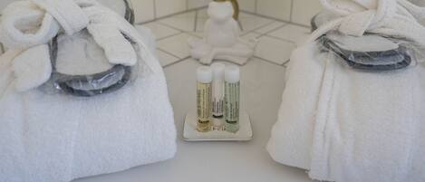 A bathroom with two towels on a rack, a small potted plant, and toiletries on a tray.