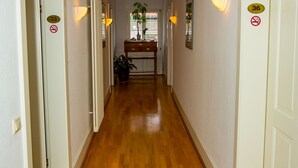 Un pasillo con suelo de madera, paredes blancas y puertas numeradas 33 y 36.