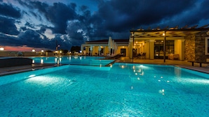 A swimming pool with a covered seating area and a building with a stone facade. - Messina Resort Hotel (Trifylia)