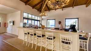 A bar area with white bar stools, a wooden ceiling, and a chandelier. - Messina Resort Hotel (Trifylia)