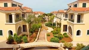 A courtyard with a central pathway, surrounded by buildings with red-tiled roofs and arched windows. - Messina Resort Hotel (Trifylia)