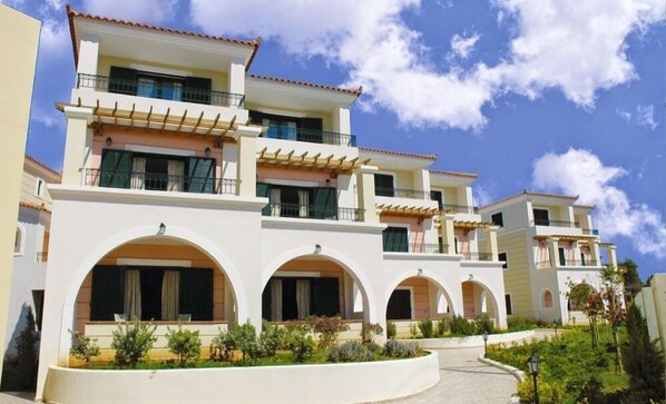 A multi-story hotel with balconies, arched windows, and a landscaped garden.