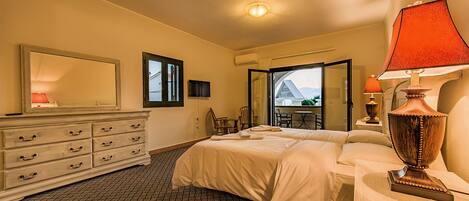 A bedroom with a bed, dresser, mirror, and a view of a balcony.