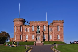 A large, historic building with a central statue, multiple towers, and a well-maintained lawn. - Dunhallin House (Inverness)