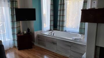 Un baño moderno con bañera, lavamanos y una televisión de pantalla plana montada en la pared.