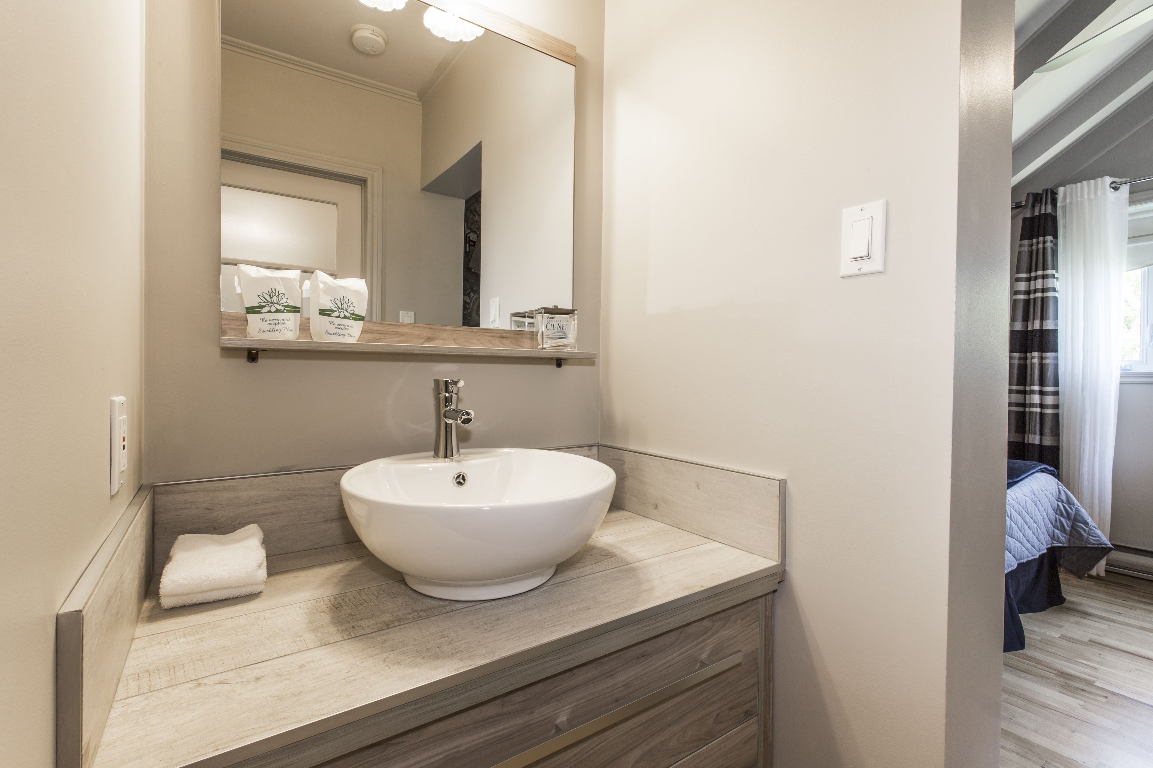 Une salle de bain avec un lavabo blanc, un meuble-lavabo en bois et un miroir au-dessus du lavabo.