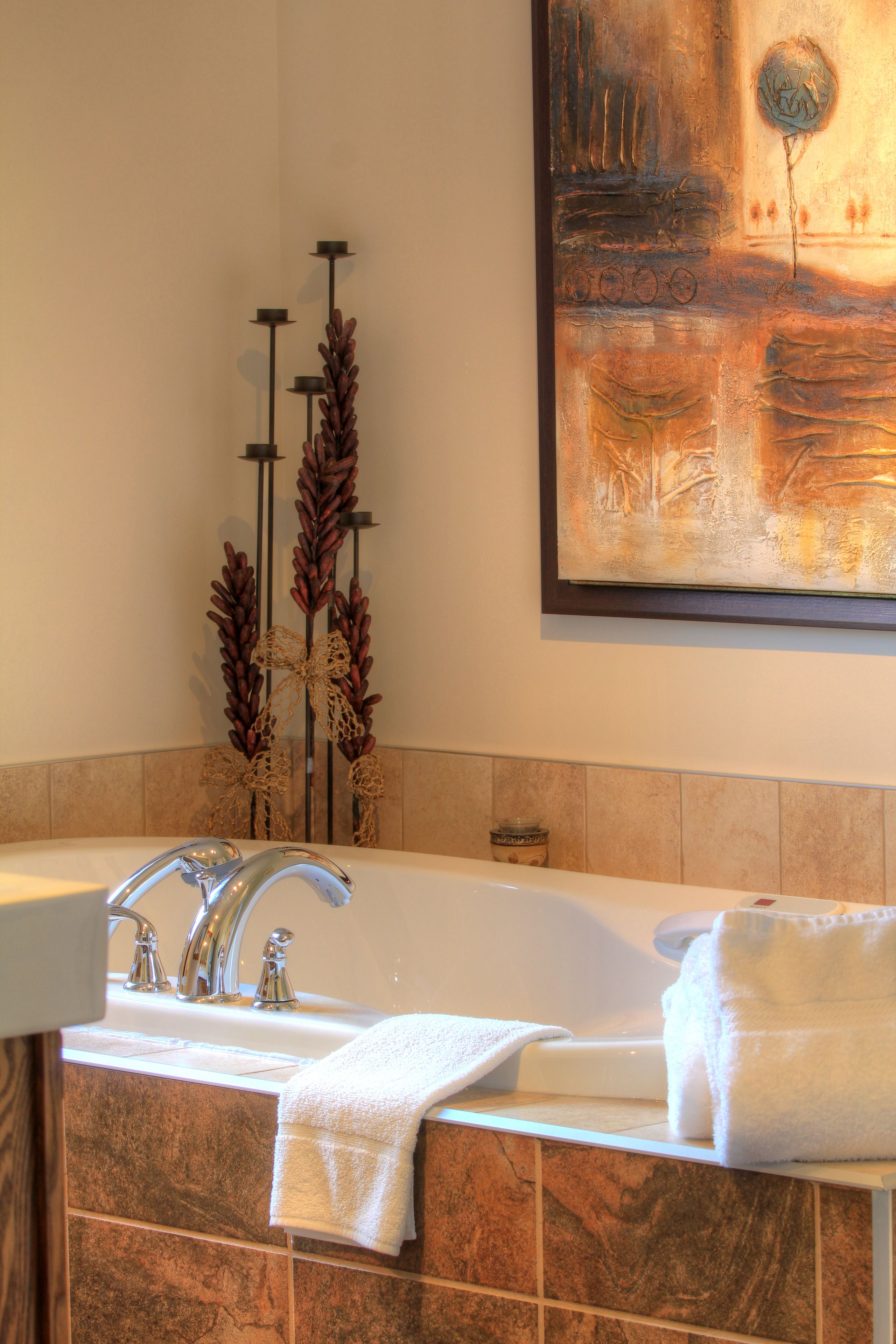 A bathroom with a large bathtub, a double sink, and decorative plants.