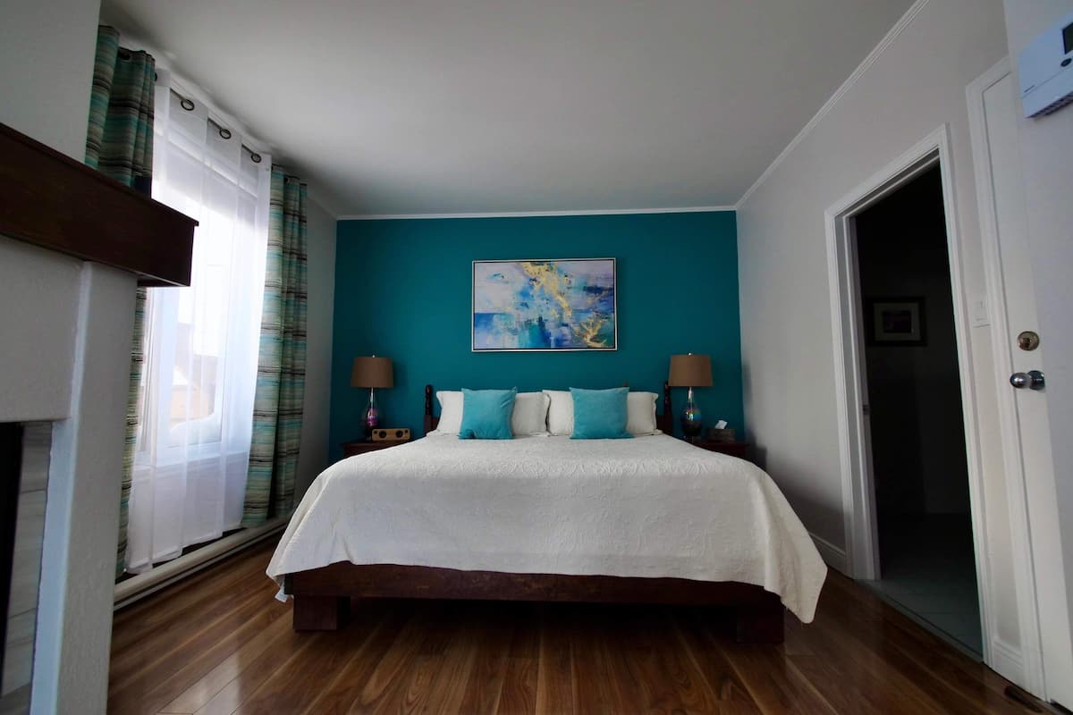Un dormitorio con una cama grande, paredes color aguamarina y un cuadro colgado encima.