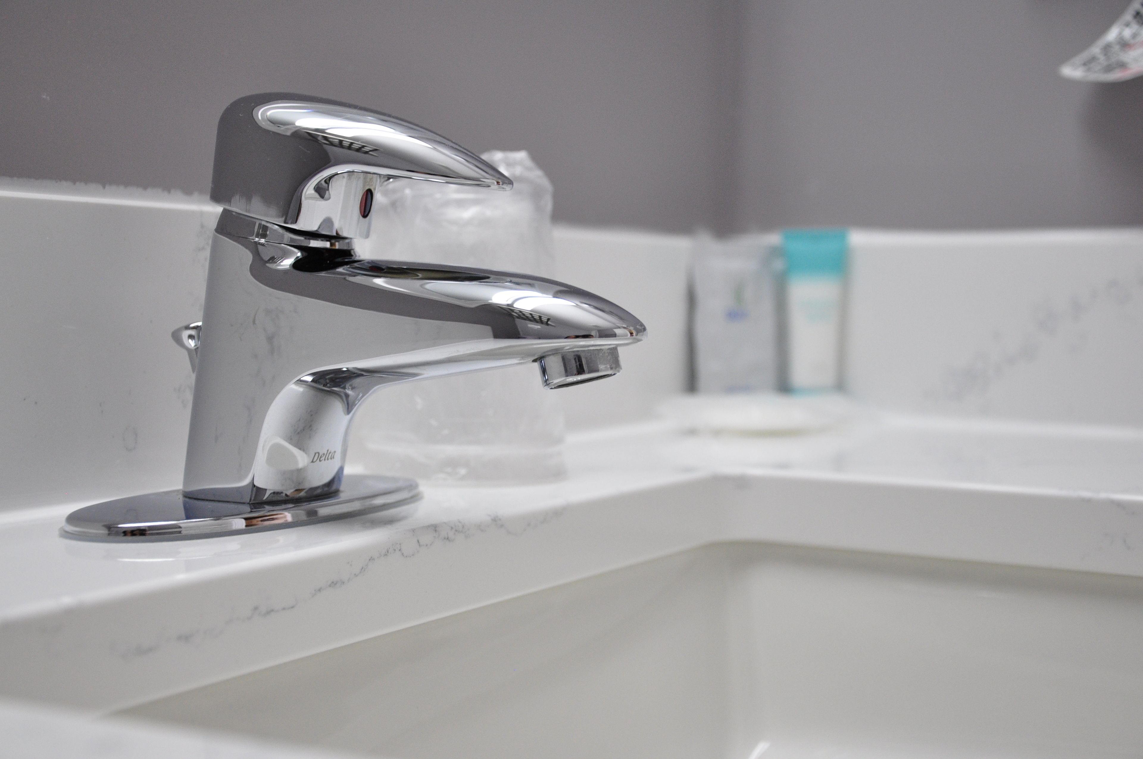 A modern bathroom with a chrome faucet, a soap dispenser, and a marble countertop.