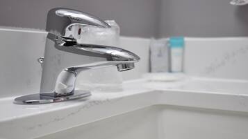 A modern bathroom with a chrome faucet, a soap dispenser, and a marble countertop.
