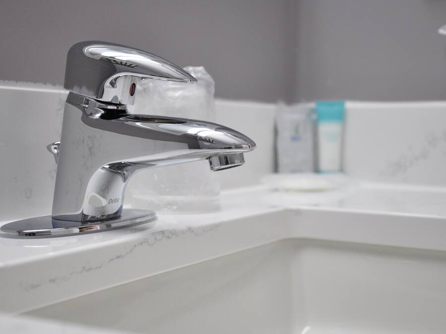 A modern bathroom with a chrome faucet, a soap dispenser, and a marble countertop.