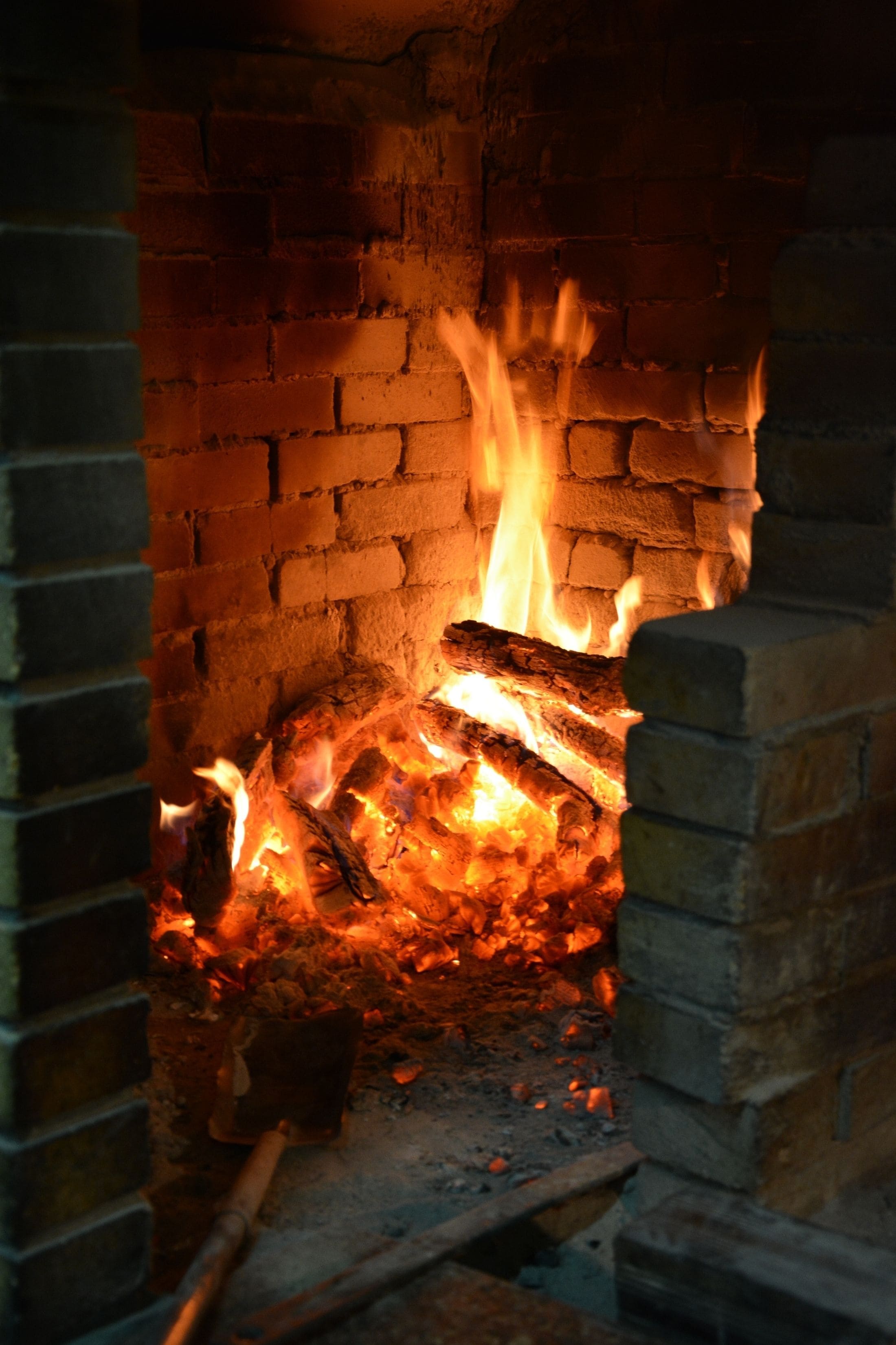 A fireplace with burning logs and a chimney.