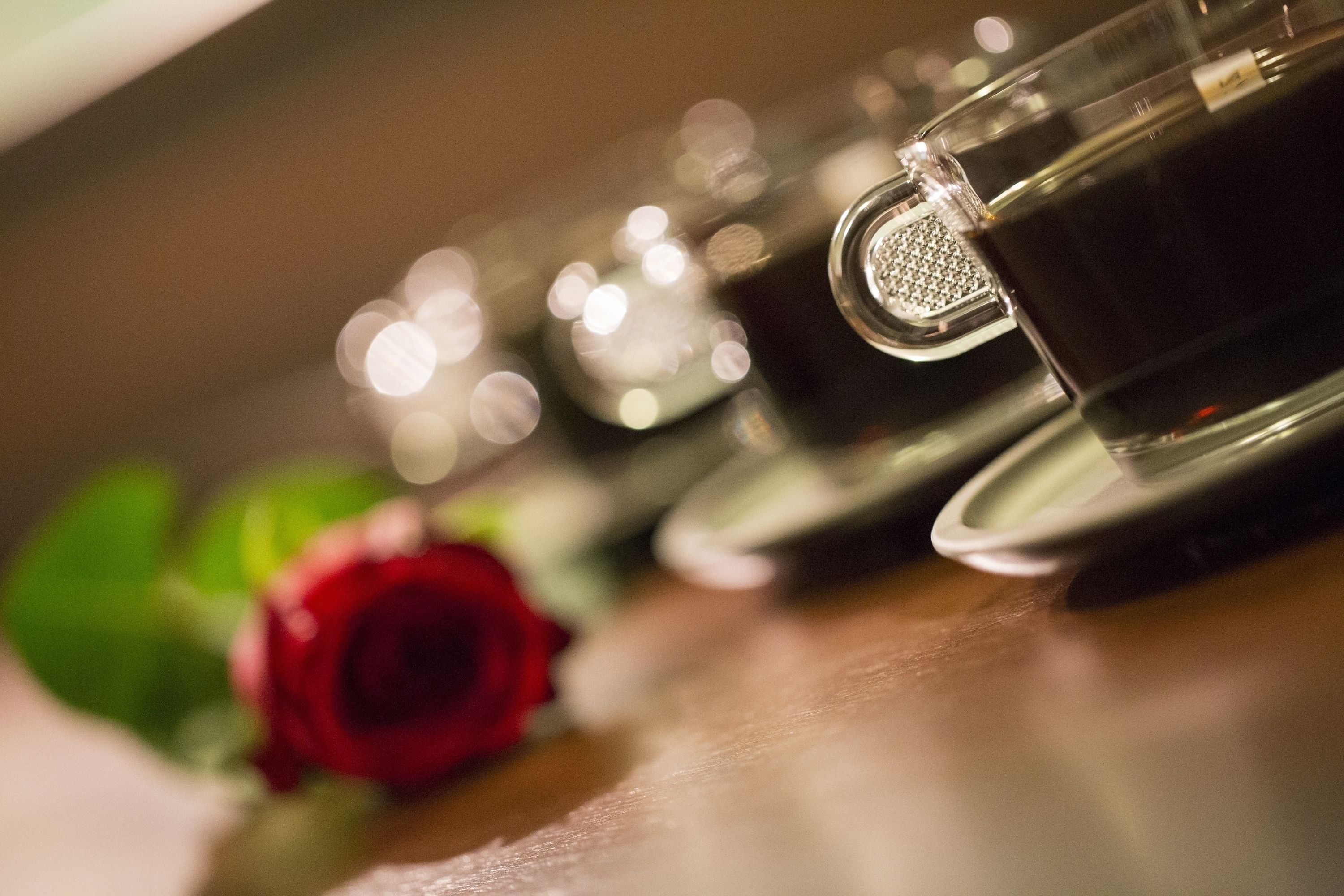 A close-up of a rose and a teapot on a table.