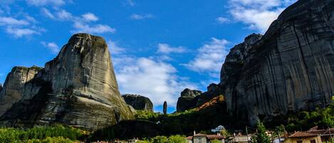 A village nestled between large rock formations with traditional houses and a clear sky.