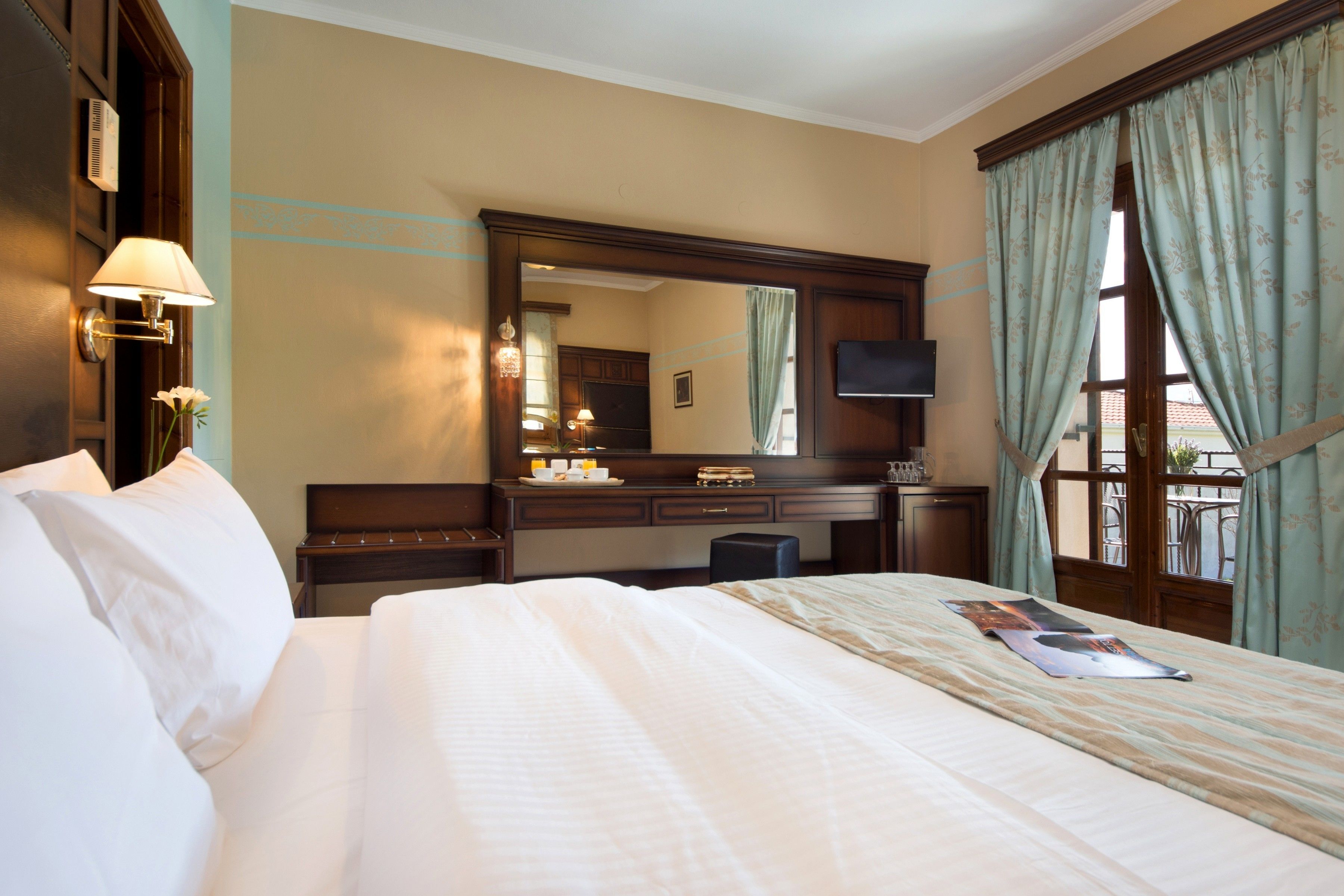 A hotel room with a large bed, a desk, a chair, a dresser, a mirror, and a television.
