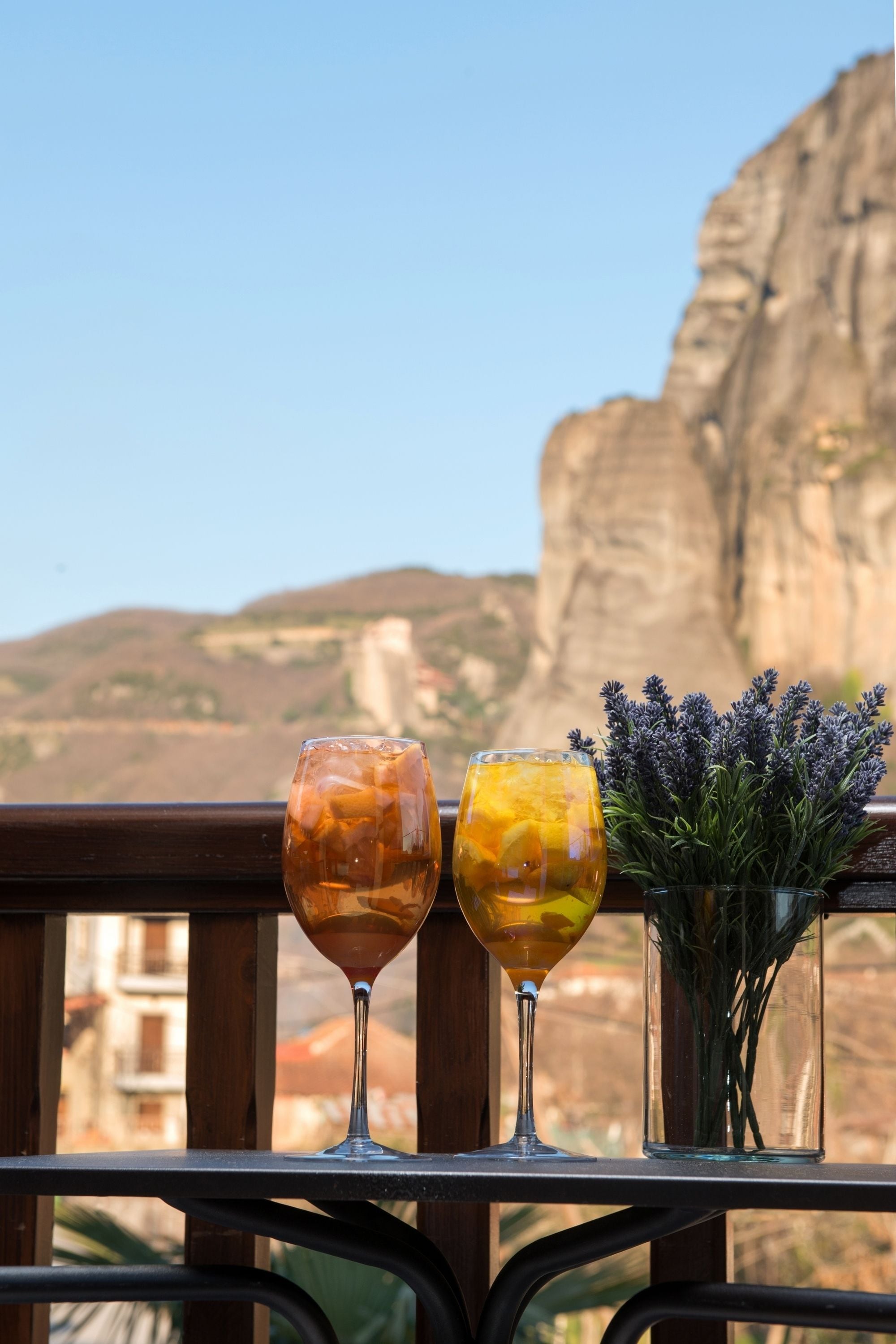 Dos vasos de bebidas en un balcón con vista a una montaña y un acantilado.