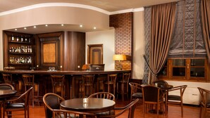 A bar area with wooden furniture, a brick accent wall, and a window with curtains. - Hotel Kastraki (Kalabaka)