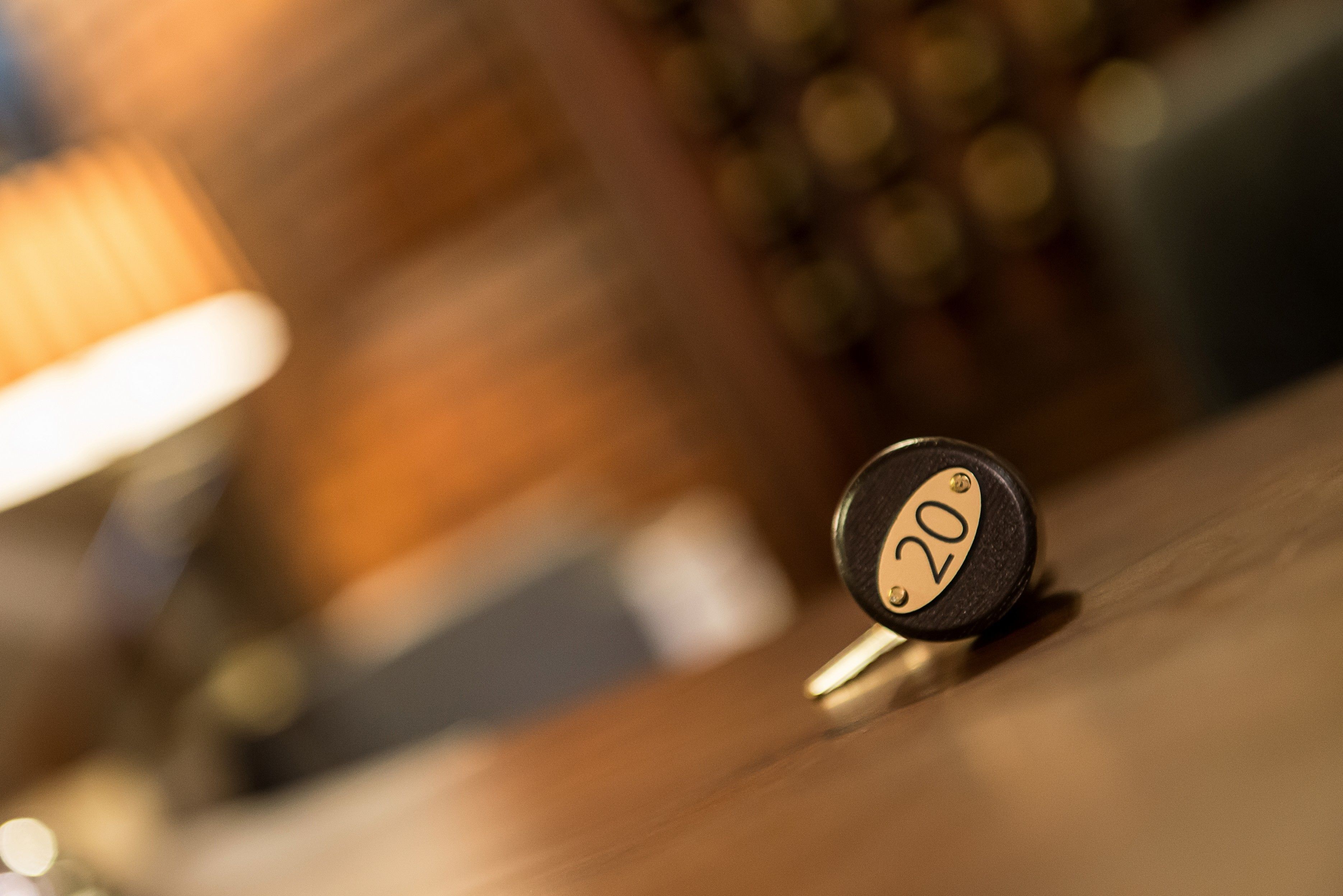 A close-up of a round, black object with a gold number "20" on it, placed on a wooden surface.