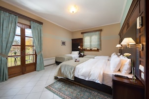 Habitación de hotel con dos camas, un ventanal con cortinas, una mesita de noche con lámpara y vistas al exterior.
