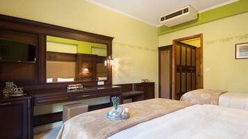 Una habitación de hotel con una cama grande, una mesita de noche, un aparador, un espejo y una puerta que da a otra habitación.