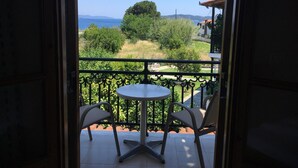 Balcón abierto con una mesa redonda y dos sillas, con vistas a un paisaje verde y colinas distantes.