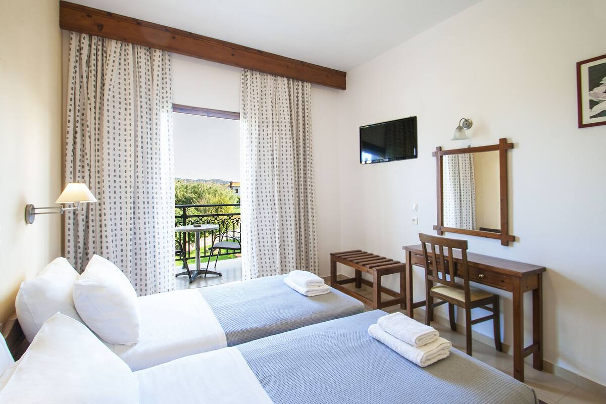 A hotel room with two beds, a desk, and a chair.