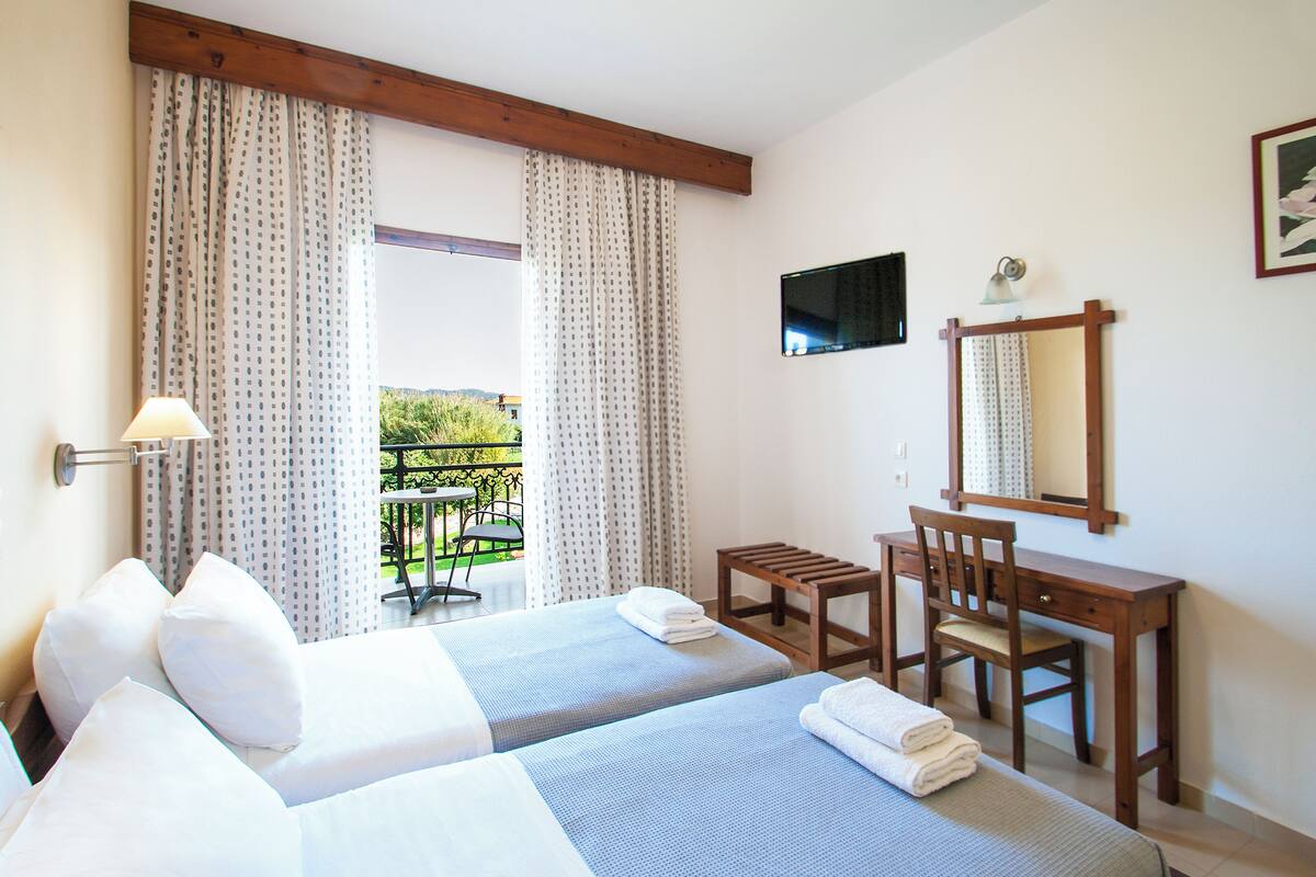 A hotel room with two beds, a desk, and a chair.