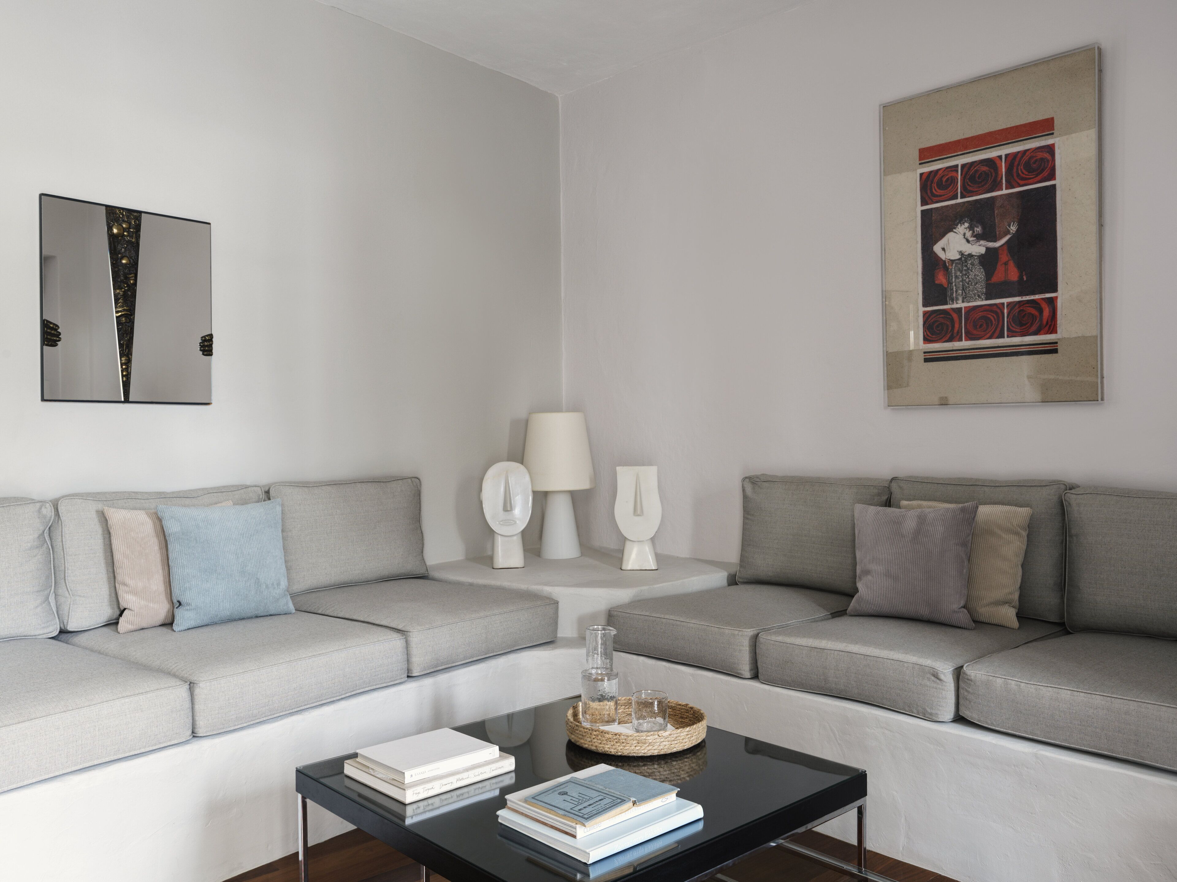 A modern living room with a grey sofa, a black coffee table, and a framed artwork on the wall.