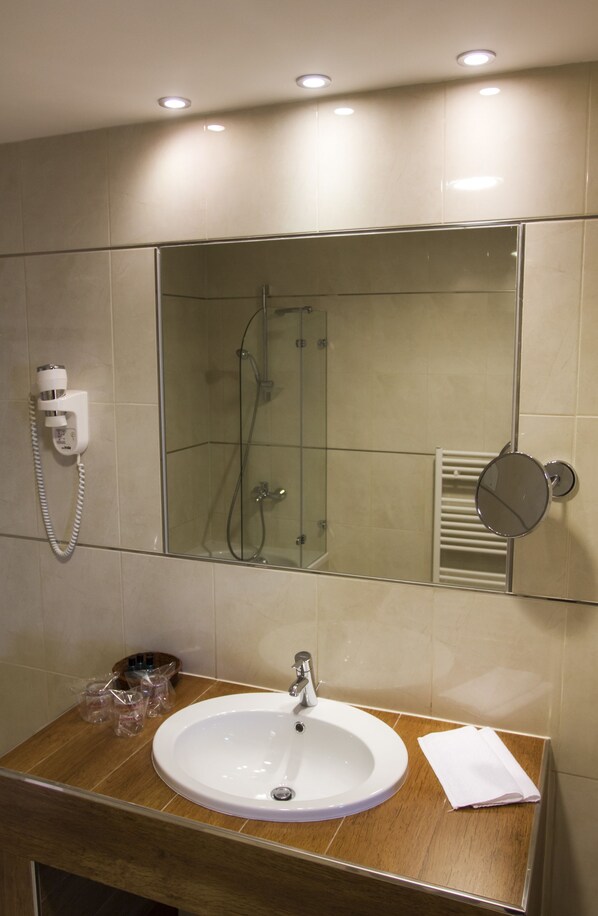 Une salle de bain avec un lavabo, un miroir et une douche.