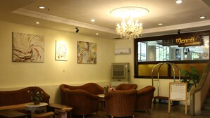 A reception area with wicker furniture, a chandelier, and artwork on the walls. - Eagle Bay Hotel (Langkawi)