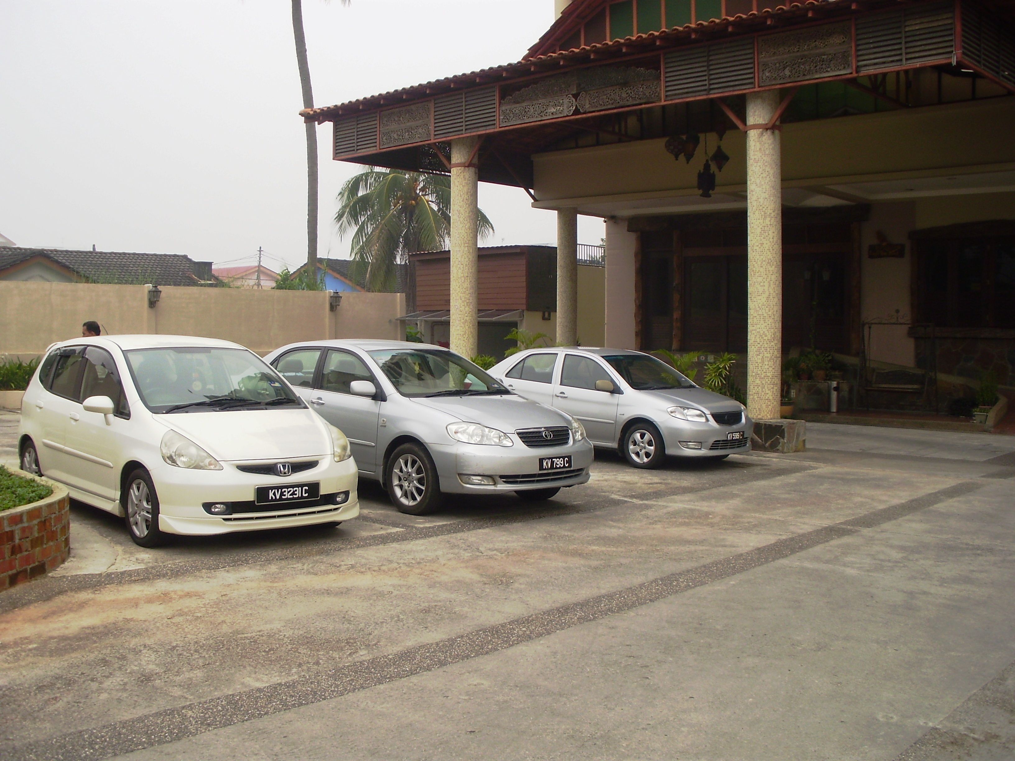 Three parked cars in front of a building with a covered entrance and columns.